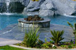 Fire ring installation in a backyard designed with a swimming pool, spa, and artifical rock waterslide and grotto in California.