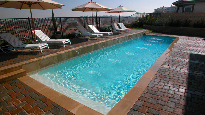 This contemporary Laguna Niguel home had a sweeping vista, but little room to move. We solved the problem with elegant geometry. A perfectly proportioned rectangular pool leaves ample entertainment space. Smooth white plaster and textured interlocking paving provide textural contrast. The precise arcs of six pencil-thin fountains make it a work of art.