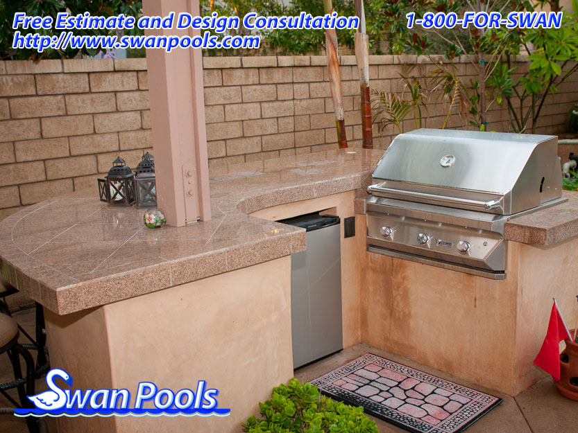 Small arc BBQ with tile top, stucco sides, and integrated into overhead patio cover.