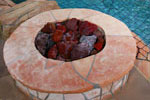 Fire ring installation integrated into a swimming pool and raised spa with an artificial rock waterfall and grotto built into a residential slope in Laguna Niguel, California.