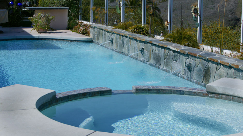 A Swan Pools custom swimming pool design with separate Pour Cantilever Concrete, crystal blue water, Red Mountain stone, and regal spouting lion heads announce that you have arrived.  A modern escape with a touch of class, elegance, and royalty fit for a king and queen.